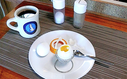 Два варёных всмятку яйца и кружка кофе на столе